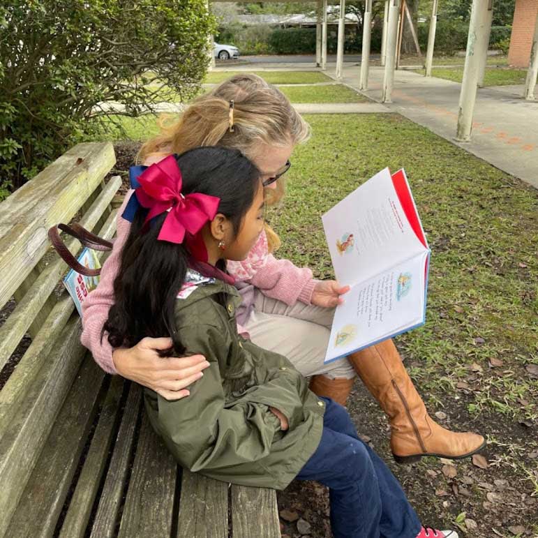 VIPS Volunteer reading with child on bench